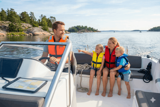 En familj med två barn är ute på en tur i sin båt. Alla har flytvästar på sig.